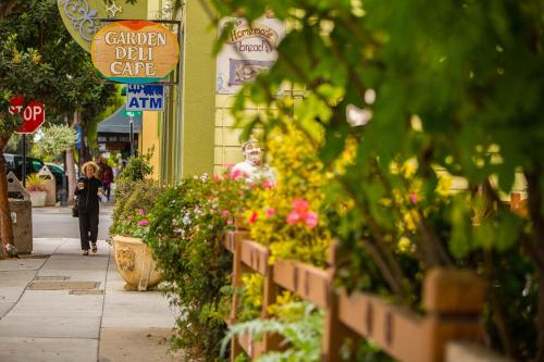 a woman walking down a sidewalk next to a flower shop at Beach Villa Home - Walk to Beaches Trails Restaurants Activities & more in Half Moon Bay