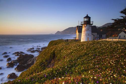 a lighthouse on a hill next to the ocean at Beach Villa Home - Walk to Beaches Trails Restaurants Activities & more in Half Moon Bay