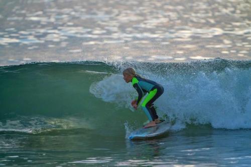 a woman riding a wave on a surfboard in the ocean at Beach Villa Home - Walk to Beaches Trails Restaurants Activities & more in Half Moon Bay