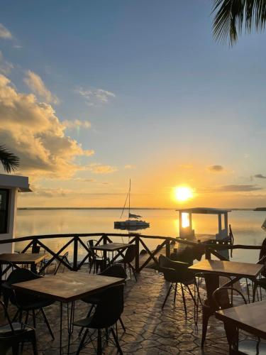 a sunset over the water with tables and chairs at Hotel Aldea 19 Bacalar in Bacalar