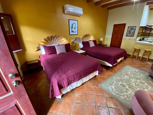 a bedroom with two beds with purple comforters at Hotel Casa María Félix in Álamos