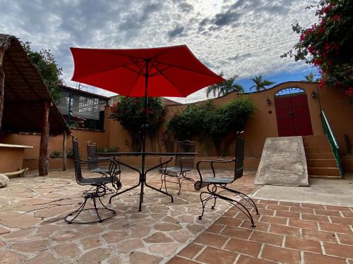 a table and two chairs with a red umbrella at Hotel Casa María Félix in Álamos