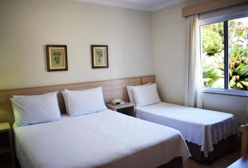 a hotel room with two beds and a window at Hotel CasaBlanca in Águas de Lindóia
