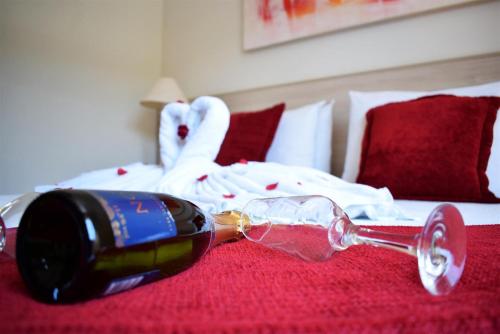 a bottle of wine and a glass on a bed at Hotel CasaBlanca in Águas de Lindóia