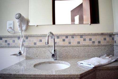 a bathroom counter with a sink and a hair dryer at Hotel CasaBlanca in Águas de Lindóia