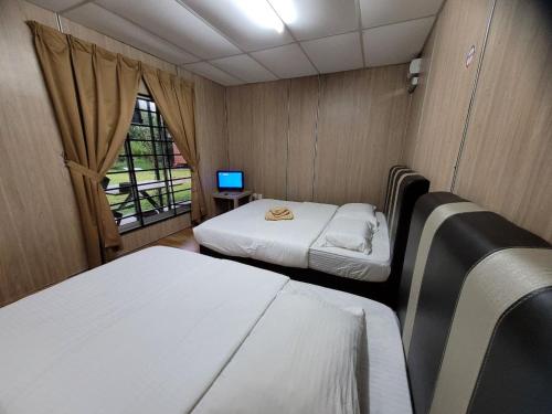 a small room with two beds and a window at Hasina Resort @Sedili in Kampong Bukit Lintang