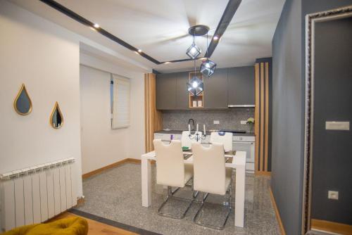 a kitchen with a white table and white chairs at Modern Mountain Apartman 202 in Kolašin