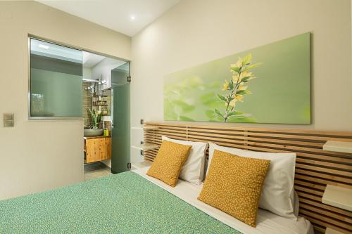a bedroom with a bed with yellow and white pillows at Olive Lemon Biophilic House & Lush Forest Garden in Vamos