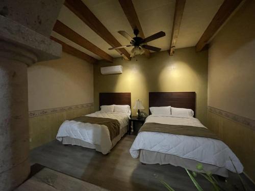 a bedroom with two beds and a ceiling fan at Hotel Real de los Alamos in Álamos