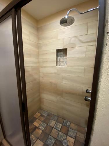 a bathroom with a shower with a tiled floor at Hotel Real de los Alamos in Álamos