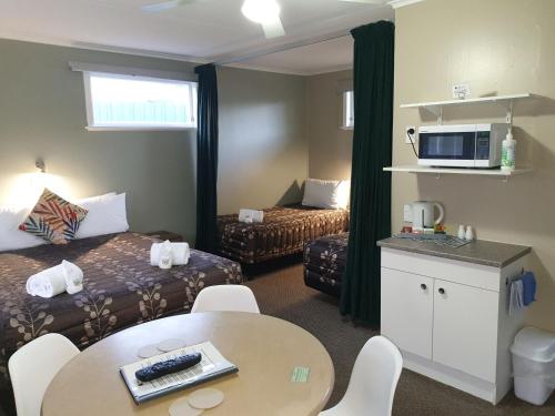 Habitación de hotel con cama, mesa y sillas en Palm Motel Waihi, en Waihi