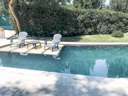 two chairs and a table next to a swimming pool at Casa en el Bosque con piscina in Ciudad Lujan de Cuyo