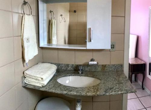 a bathroom with a sink and a mirror at Apartamento Pé na Areia e águas tranquilas no centro de Guarapari in Guarapari