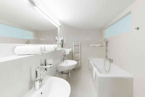 a white bathroom with a sink and a toilet at Hotel Split in Kadaň