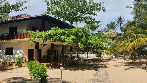 a house on the beach with trees in front of it at Tropical Garden in Tangalle