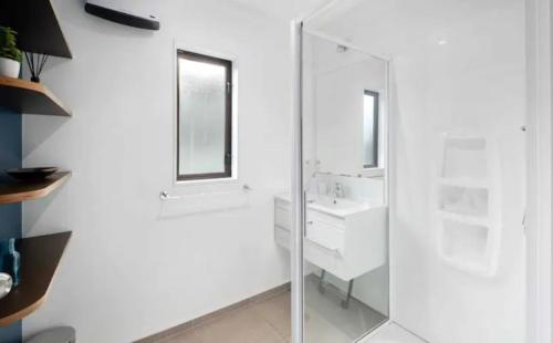 a white bathroom with a sink and a mirror at Fantastic Views, Close to Town 2 Bedroom Apartment in Queenstown