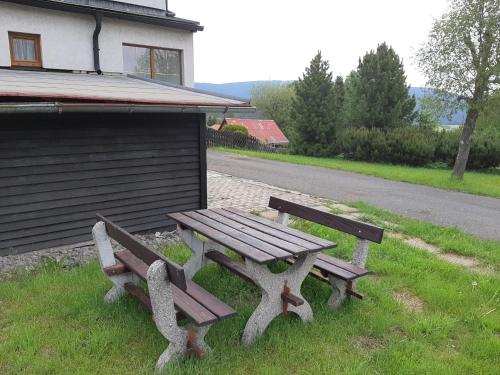 a wooden picnic table sitting in the grass next to a building at Naproti Klínovci in Jáchymov