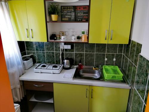 eine kleine Küche mit gelben Schränken und einem Waschbecken in der Unterkunft Nexus Happy in Miercurea Ciuc