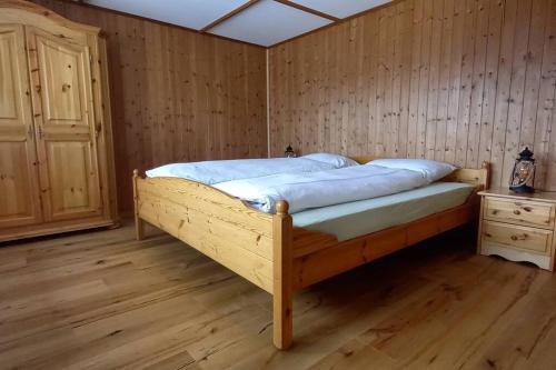 Cama de madera en habitación con suelo de madera en Känzeli - Ferienwohnung mit Traumaussicht, en Beatenberg