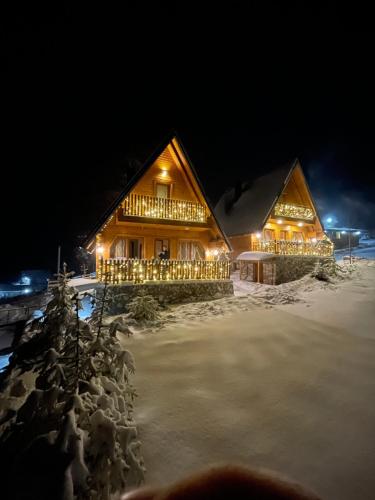 a log cabin in the snow at night at Villa Dardania in Peje