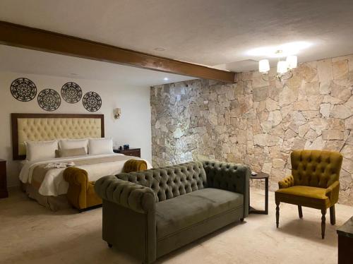 a bedroom with a bed and a couch and a stone wall at Real Hispano in Valladolid