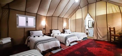 eine Gruppe von 4 Betten in einem Zimmer in der Unterkunft Sunset luxury camp in Adrouine