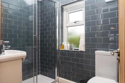 a bathroom with a toilet and a shower with blue tiles at Relaxation by Olauda SA - 3 Bed House with Free Parking in Bristol
