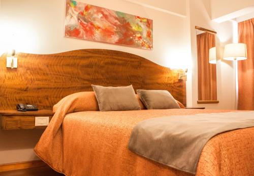 a bedroom with a large bed with a wooden headboard at HOTEL ROYAL PRINCESS in Mendoza