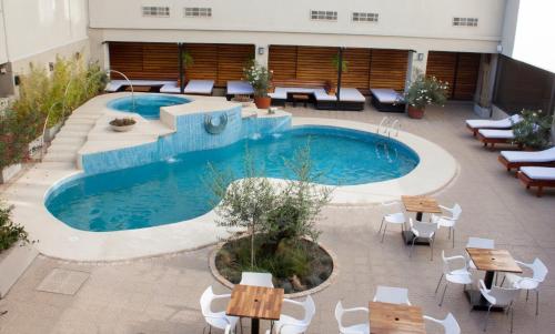 una piscina con mesas y sillas junto a un edificio en HOTEL ROYAL PRINCESS en Mendoza