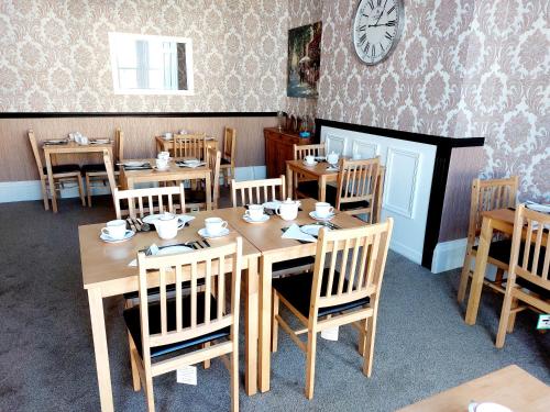 uma sala de jantar com mesas e cadeiras e um relógio na parede em The Patricia em Torquay