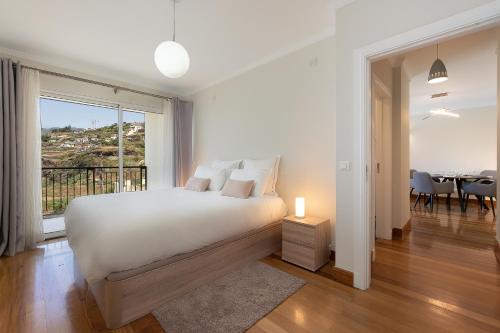 a white bedroom with a bed and a dining room at Infinity pool & Amazing Sunset Ocean View in Funchal