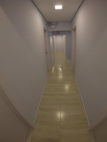 a long hallway with white walls and a wooden floor at Hotel e Pousada Magic in Penha