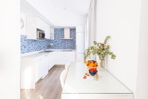 格拉纳达Apartamentos con encanto en el centro de Granada的白色的厨房,配有一张桌子和一碗橙子
