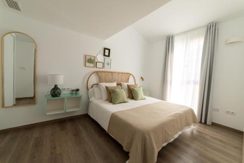 a white bedroom with a large bed and a mirror at Apartamentos con encanto en el centro de Granada in Granada