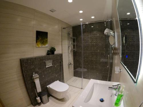 a bathroom with a shower and a toilet and a sink at Luxury Apartment in DAMAC Towers in Amman