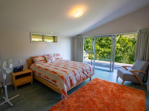 a bedroom with a bed and a large window at Golden Paradise - Rangihaeata Holiday Home in Takaka