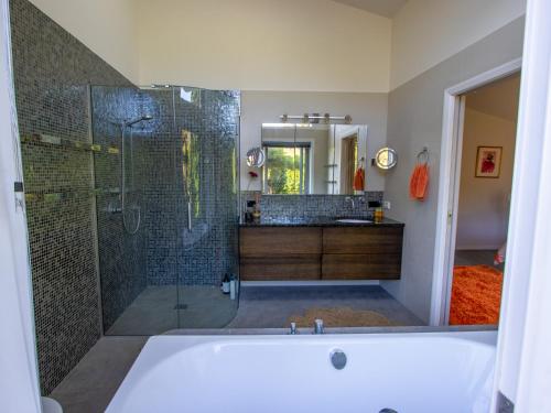 a bathroom with a tub and a glass shower at Golden Paradise - Rangihaeata Holiday Home in Takaka