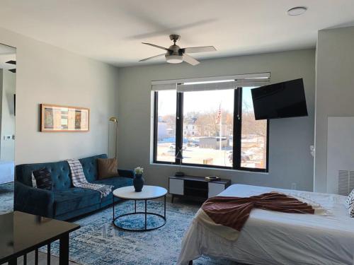 a bedroom with a bed and a couch and a tv at Sleepover Studio Apartments Des Moines in Des Moines