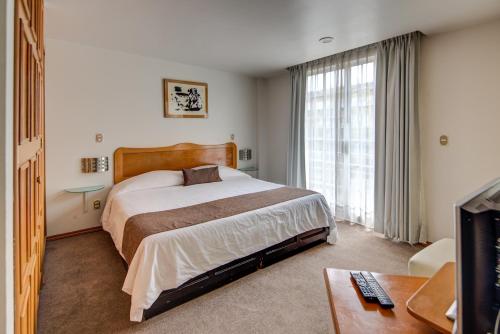a hotel room with a bed and a television at Grupo Kings Suites - Bosques de Duraznos 78 in Mexico City