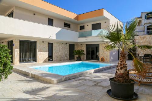 einen Pool vor einem Haus mit einer Palme in der Unterkunft Villa Kajgo-Pag in Pag