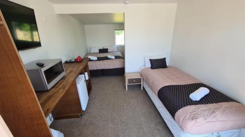a small bedroom with two beds and a tv at Woodstock Hotel in Hokitika