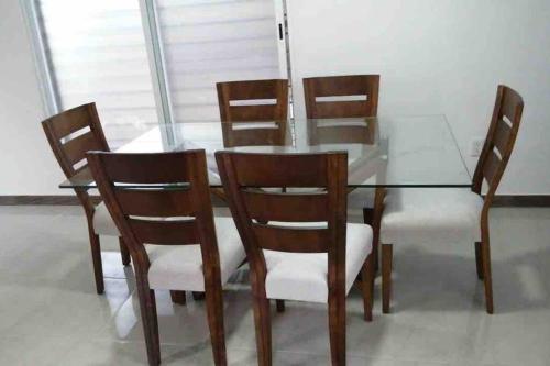 a glass dining room table with wooden chairs and a glass table and chairsearcher at Un pedacito de arena en Cancún in Cancún