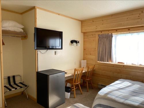 a room with a bed and a desk and a television at Stork Nest Inn in Smithers