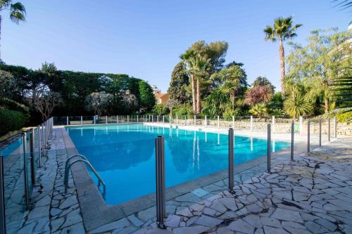 - une piscine bordée d'arbres et de palmiers dans l'établissement Apartment In A Residence With Swimming Pool Wifi, à Cannes