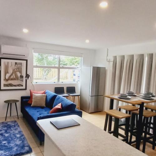 a living room with a blue couch and a table at Harbourside 29B ~ Boat Parking in Coromandel Town