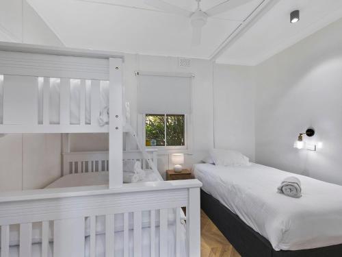 a white bedroom with two beds and a window at Oceanside Cottage in The Entrance