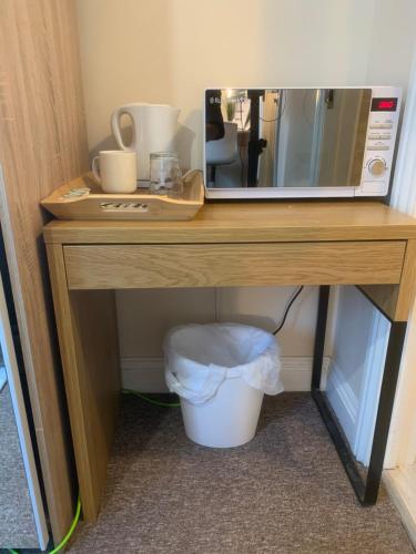 a wooden table with a microwave and a trash can at Cosy Room With Private Entrance & Ensuite in Reading