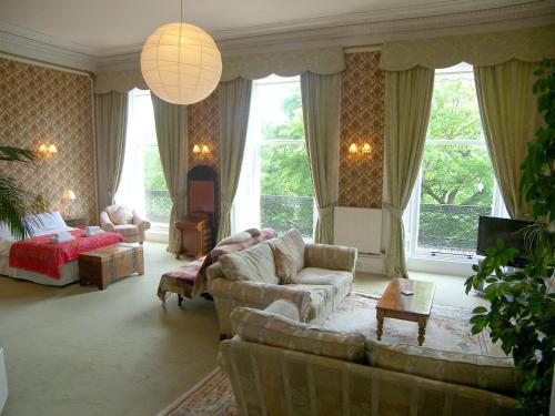 sala de estar con sofá, cama y ventanas en Regent Terrace, Central and Charming, Quiet en Edimburgo