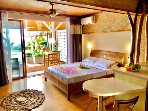 sypialnia z łóżkiem i stołem oraz balkonem w obiekcie Chambre totalement équipée avec vue imprenable!!! w mieście Punaauia