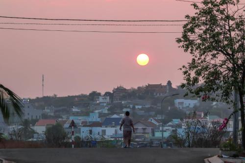 a person standing on a road looking at the sunset at Cô Tư's Homestay in Phan Thiet